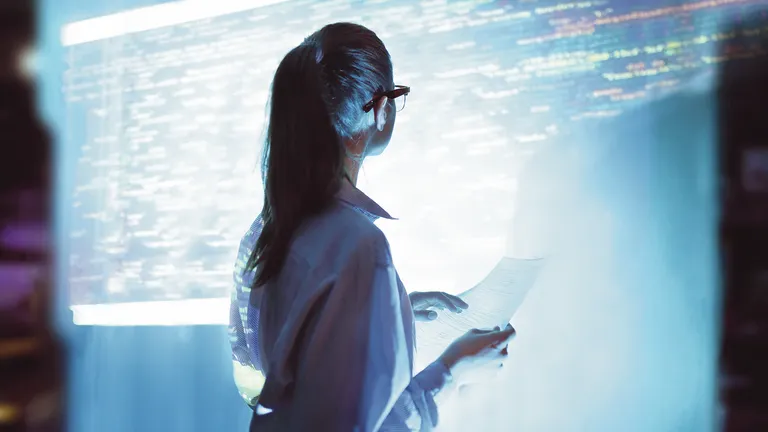 háttal álló nő néz egy digitális táblát