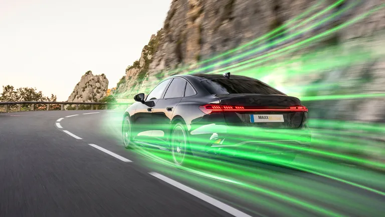 Fekete autó zöld csíkokat húz miközben egy sziklás környéken megy