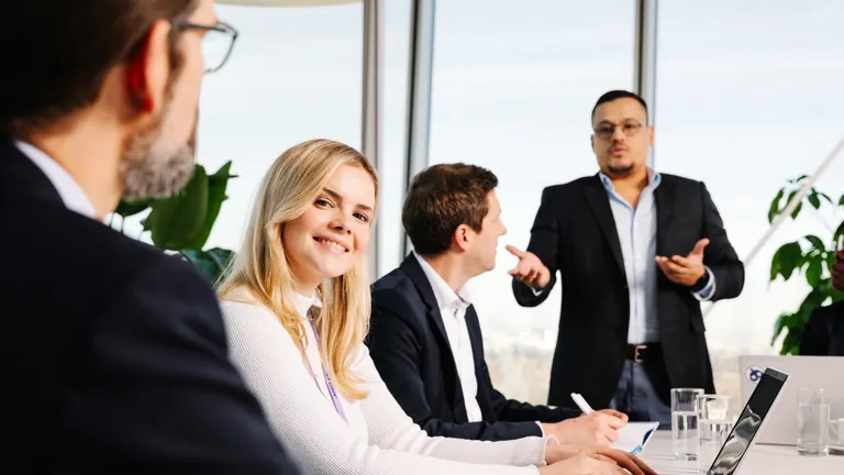 Hivatalos tárgyaláson egy lány kedvesen mosolyog 