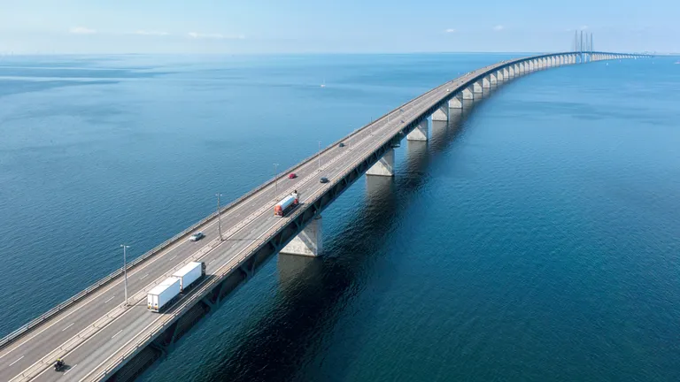 Tartályautó, kamion és személyautók haladnak a hídon a tenger felett